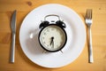 intermittent fasting concept alarm clock on kitchen table Royalty Free Stock Photo