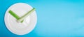 Intermittent fasting, diet concept. Banner. An empty plate as a dial and pods of a seler as a clock hands on a blue background Royalty Free Stock Photo