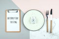 Intermittent fasting diet concept. Empty plate with alarm clock, note notepad. Flat lay, top view Royalty Free Stock Photo
