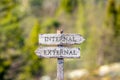 internal external text carved on wooden signpost outdoors in nature.