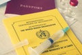 International Certificate of Vaccination with a Syringe, passport of a foreign citizen and a Ampule on table