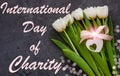 International Day of Charity card message sign.Donations concept.White tulip flowers and heart card tag with pink ribbon Royalty Free Stock Photo