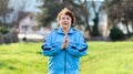International Day of Older Persons. Portrait of a smiling elderly woman in sportswear, meditating in a park. Grass in Royalty Free Stock Photo