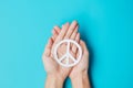 International Day of Peace. Hands holding white paper Peace symbol on blue background. Freedom, Hope, World Peace day 21 September