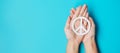 International Day of Peace. Hands holding white paper Peace symbol on blue background. Freedom, Hope, World Peace day 21 September