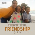 International friendship day text with happy biracial couple and children embracing on sunny beach Royalty Free Stock Photo