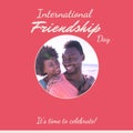 International friendship day text on pink with happy african american couple on sunny beach Royalty Free Stock Photo