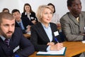 International group of business people listening to presentation at tables Royalty Free Stock Photo