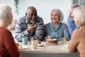 International group of positive elderly people drinking tea with cake Royalty Free Stock Photo