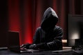 International hacker in black pullover and black mask trying to hack government on a black and red background. Cyber crime .