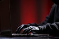 International hacker in black pullover and black mask trying to hack government on a black and red background. Cyber crime .