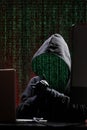 International hacker in black pullover and black mask trying to hack government on a black and red background. Cyber crime .