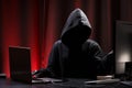 International hacker in black pullover and black mask trying to hack government on a black and red background. Cyber crime .