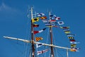 International maritime signal flags on a flagpole and masts on a sailing ship with a blue sky in the background. Royalty Free Stock Photo
