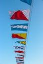 International maritime signal flags are waving on wind under blue cloudy sky