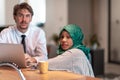 International multicultural business team.Man and muslim woman with hijab working together using smartphone and laptop Royalty Free Stock Photo