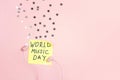 International Music Day background with earphones and stars on pink background