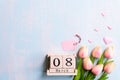 International Women`s Day concept. Pink tulips and paper hearts with March 8 text on wooden block calendar on blue wooden Royalty Free Stock Photo