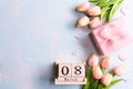 International Women`s Day concept. Pink tulips and paper hearts with March 8 text on wooden block calendar on blue wooden Royalty Free Stock Photo