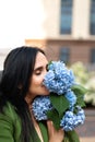 International Women's Day. Happy serene woman holding and smelling bouquet of spring hydrangea flowers, lifestyle outdoor