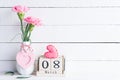 International Womens day concept. Pink carnation flower in vase and red heart with March 8 text on wooden block calendar on white Royalty Free Stock Photo