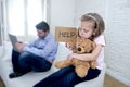 Internet addict father using digital tablet pad ignoring little sad daughter bored hugging teddy bear