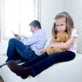 Internet addict father using mobile phone ignoring little sad daughter bored hugging teddy bear Royalty Free Stock Photo