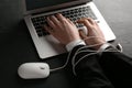 Internet addiction. Closeup of man typing on laptop at black table, hands tied with computer mouse cable Royalty Free Stock Photo