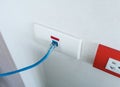 Internet blue cable plug into the white network outlet Royalty Free Stock Photo