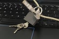 Internet cable passing through a closed iron lock with keys on a laptop keyboard data protection concept cybercrime