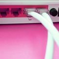 The Internet cable plugs are connected to the Internet router, which lies on a bright pink background. Items required for Internet Royalty Free Stock Photo