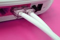 The Internet cable plugs are connected to the Internet router, which lies on a bright pink background. Items required for Internet Royalty Free Stock Photo
