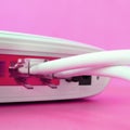 The Internet cable plugs are connected to the Internet router, which lies on a bright pink background. Items required for Internet Royalty Free Stock Photo