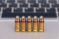 Internet dangers concept. Close up of bullets and laptop keyboard Royalty Free Stock Photo