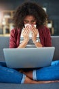 The internet is filled with tips for treating the flu. a young woman blowing her nose while using a laptop on the sofa Royalty Free Stock Photo