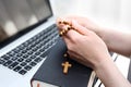 Internet Mass. A woman prays at the rosary.