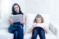 Internet network addict mother using digital tablet pad ignoring little sad daughter left alone bored Royalty Free Stock Photo