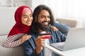 Internet Purchases. Portrait Of Smiling Muslim Couple Using Laptop And Credit Card Royalty Free Stock Photo