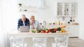 Cheerful elderly european man and wife look at laptop and pay money through banking with credit card