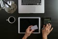 Internet shopping concept.Top view of hands working with calculator and laptop and credit card and tablet computer on dark wooden