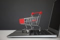 Internet shopping. Laptop with small cart on table against grey background Royalty Free Stock Photo