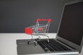 Internet shopping. Laptop with small cart on table against grey background Royalty Free Stock Photo