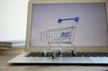 Internet shopping. Laptop with small cart on table, closeup Royalty Free Stock Photo