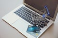 Internet shopping. Modern laptop with small cart and credit cards on light table Royalty Free Stock Photo