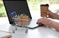 Internet shopping. Small cart with bags near woman using laptop indoors Royalty Free Stock Photo