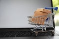 Internet shopping. Small cart with boxes on modern laptop, space for text Royalty Free Stock Photo