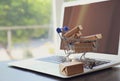 Internet shopping. Small cart with boxes and modern laptop on table indoors, space for text