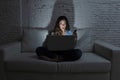 Internet social network addict woman using laptop computer and mobile phone on couch at night Royalty Free Stock Photo