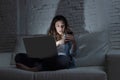 Internet social network addict woman using laptop computer and mobile phone on couch at night Royalty Free Stock Photo