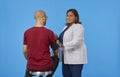 Internist looking at camera and smiling while measuring blood pressure of unrecognizable patient